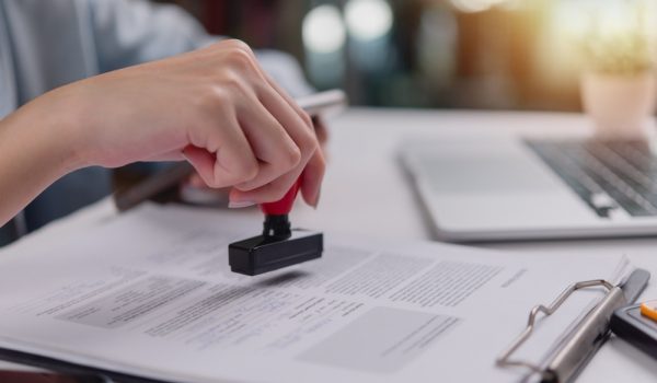 Close-up,Of,Hand,Using,A,Red,Stamp,On,A,Legal