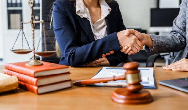 Two,Female,Lawyers,In,Business,Suits,Shake,Hands,At,Wooden